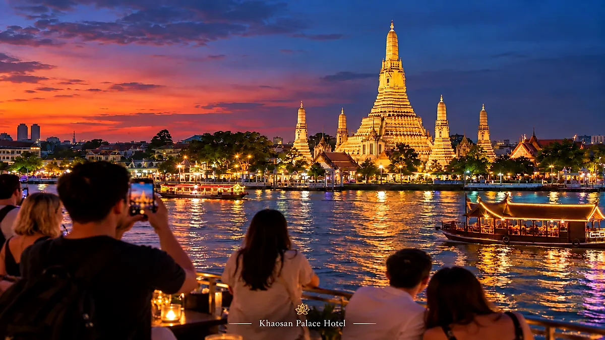 Travelers viewing Wat Arun across the Chao Phraya River at blue hour