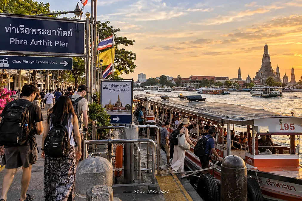 Travelers boarding a Chao Phraya boat at Phra Athit Pier at sunset